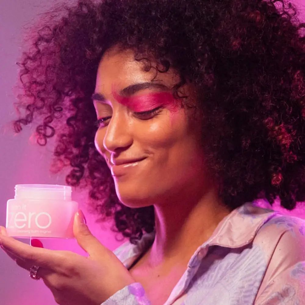 Frau hält einen rosa Tiegel. Aufschrift "clean it zero". Hintergrund rosa und lila.