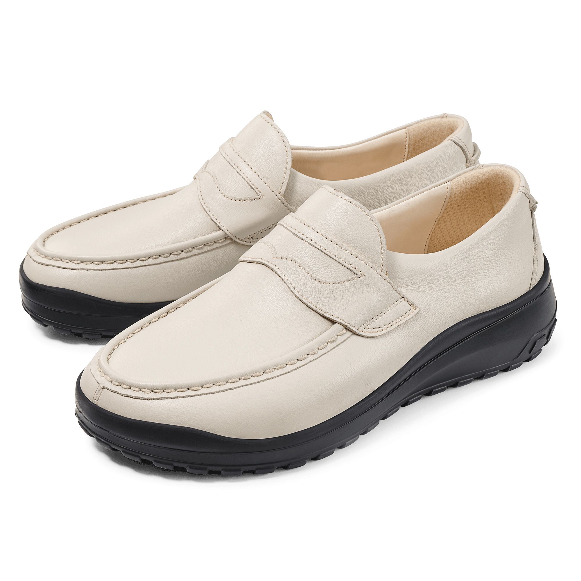 Zwei cremefarbene Slipper mit schwarzer Sohle. Klassisches Design mit Ziernaht und Riemen. Breiter Schnitt.
