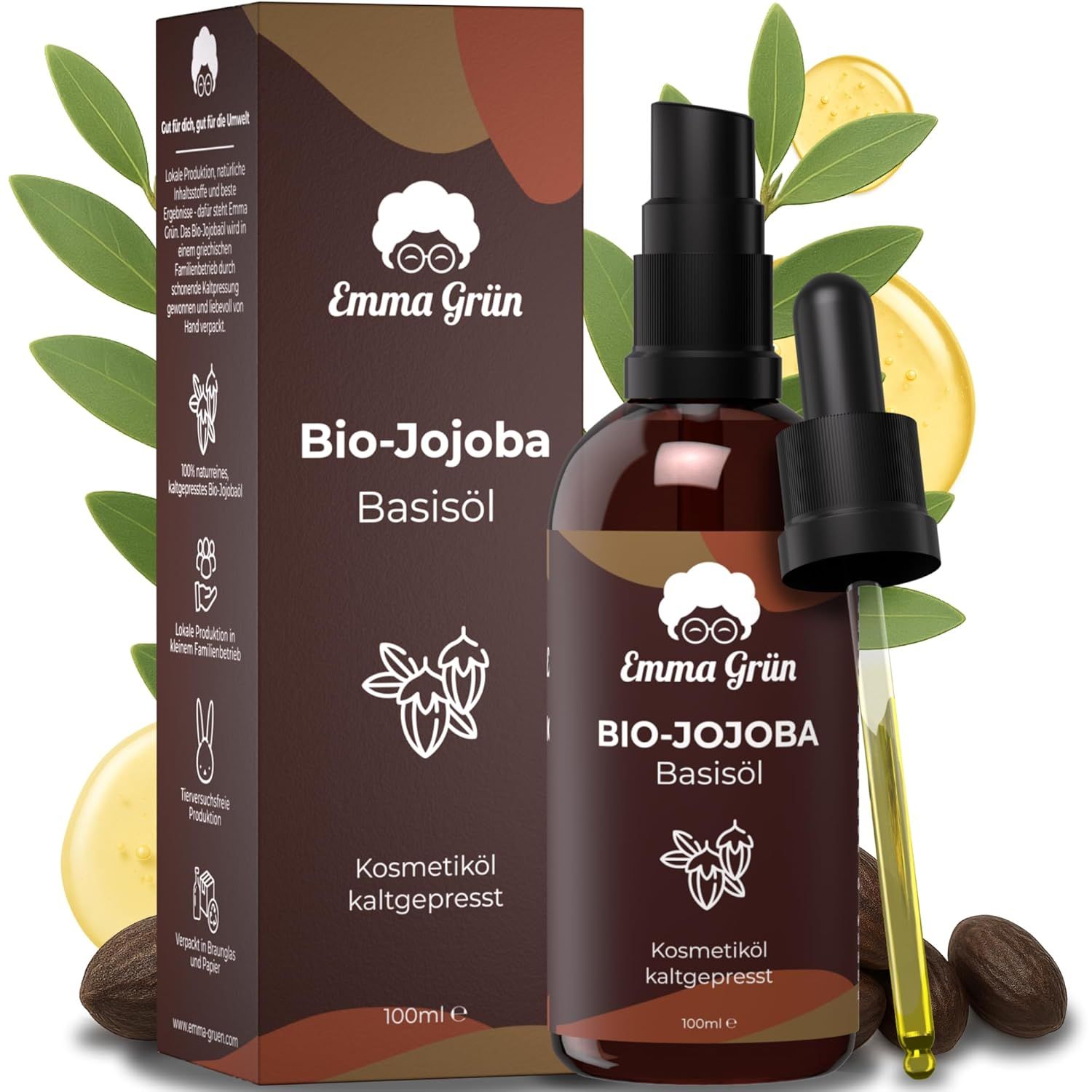 Braune Flasche und Karton mit Produktinformationen. Aufschrift: Emma Grün Bio-Jojoba Basisöl. Mit Pipette und Blättern.