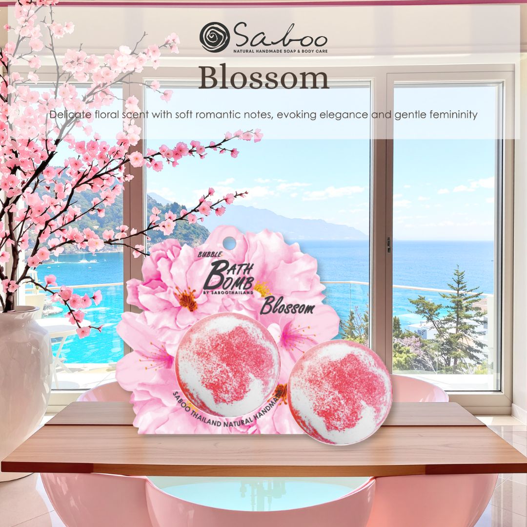 Zwei Badbomben mit Blütenmotiv auf Holzbrett. Hintergrund: Fenster mit Meerblick. Text: Blossom.