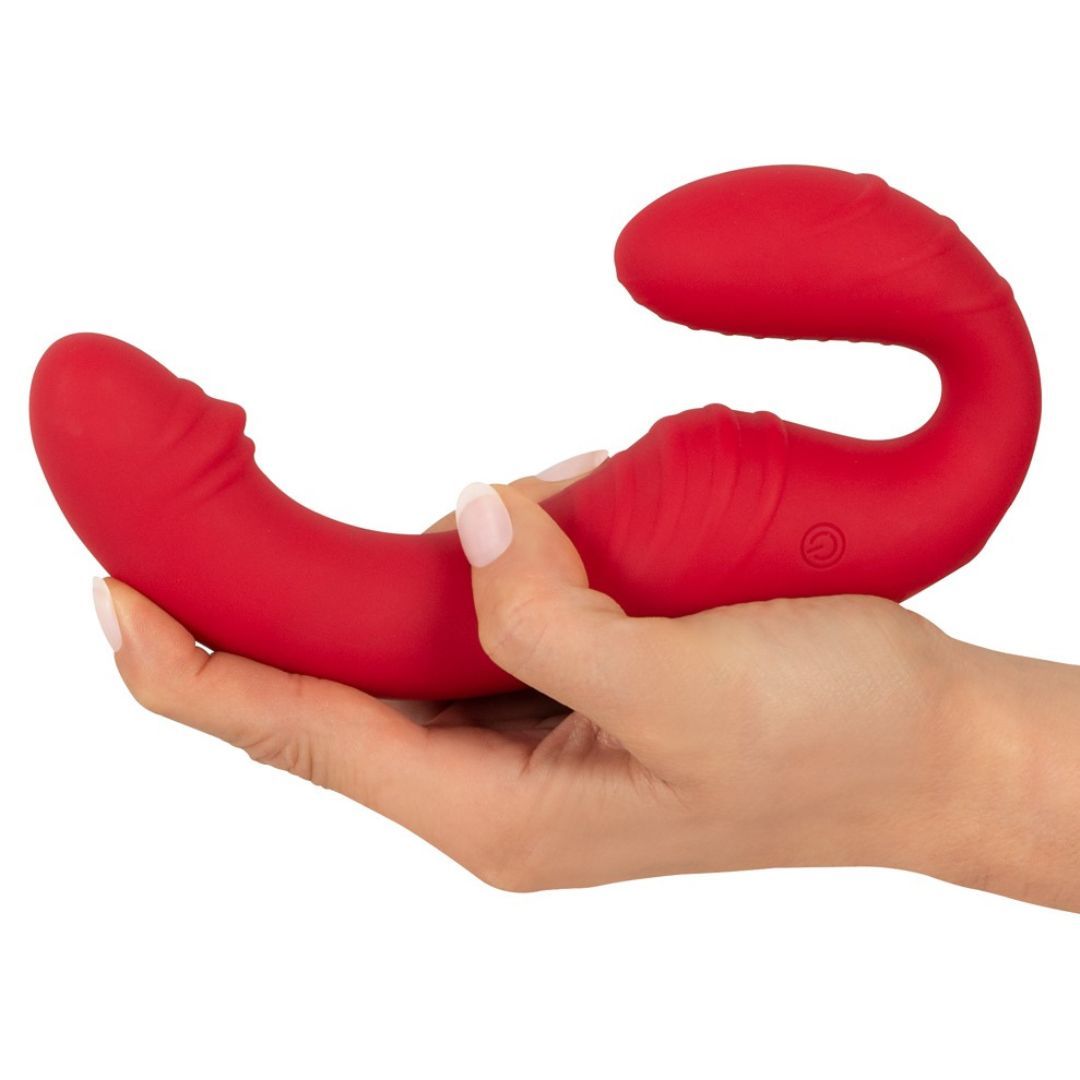 Roter Vibrator in einer Hand gehalten. Das Gerät hat eine gebogene Form mit zwei abgerundeten Enden.