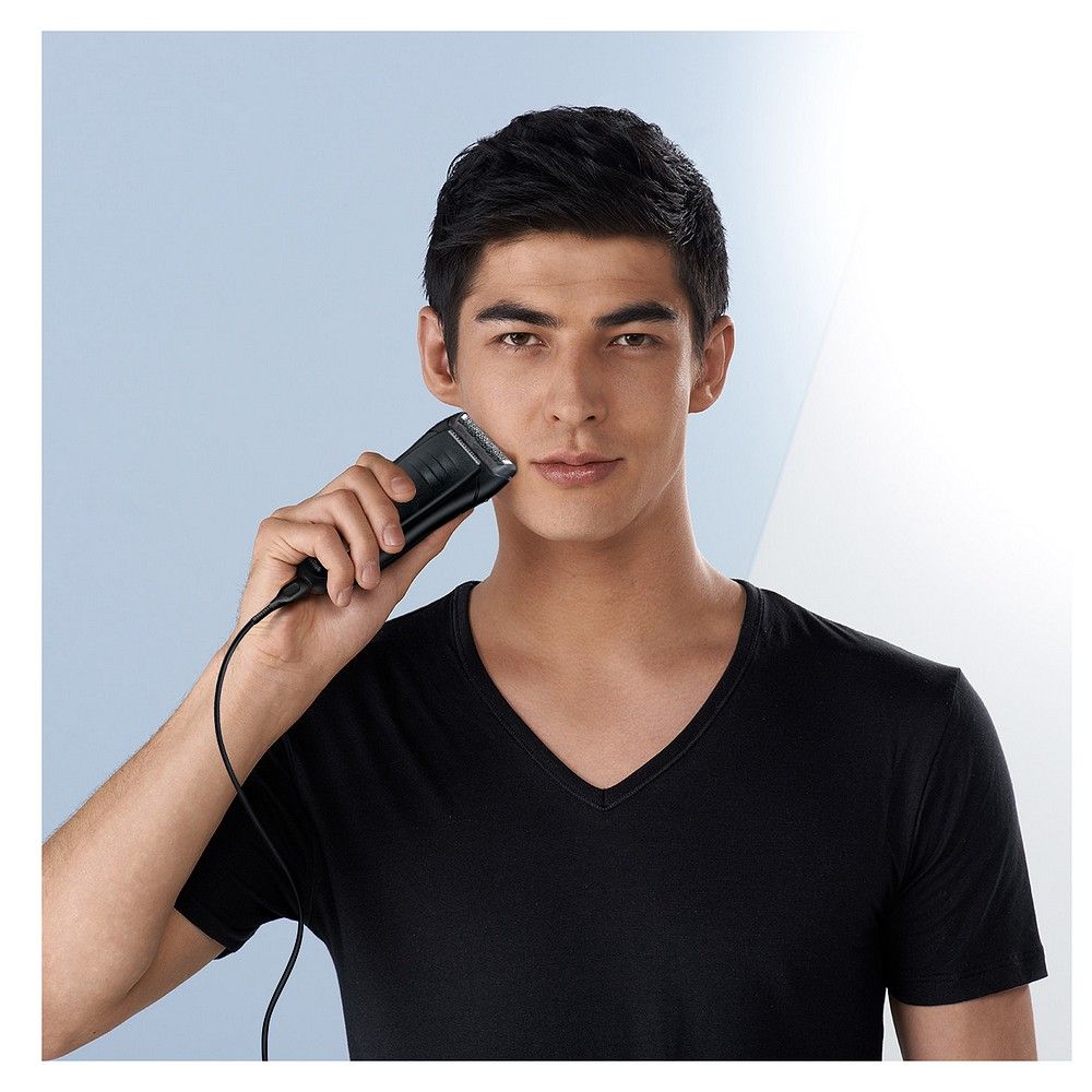 Mann rasiert sich mit einem Braun Series 1 Elektrorasierer, der über ein Kabel verbunden ist.