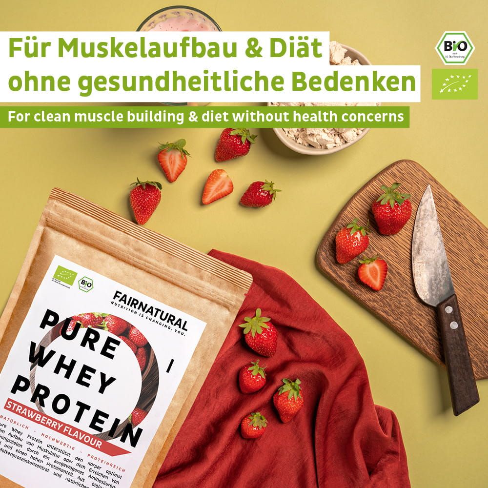 FAIRNATURAL Bio Whey Protein Erdbeergeschmack Pulver auf rotem Tuch, umgeben von Erdbeeren, Schüssel mit Haferflocken und Messer auf Holzbrett.