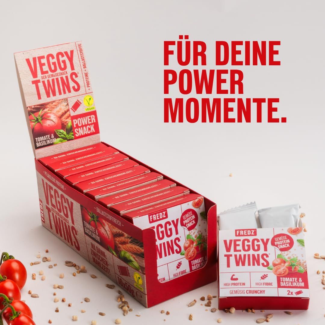 Geöffnete Displaybox mit FREDZ VeggyTwins® - Gemüsiger Proteinsnack. Einzelne Packungen mit Tomate & Basilikum. Rote Verpackung.