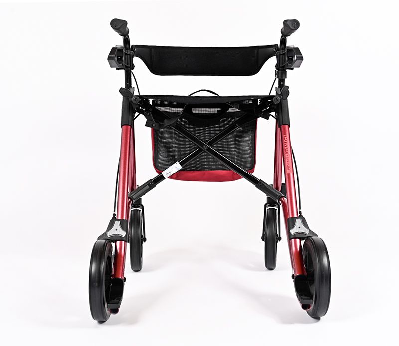 Rot-schwarzer Rollator mit vier Rädern. Er hat einen Korb, eine Rückenlehne und Handgriffe. Der Rahmen ist rot.