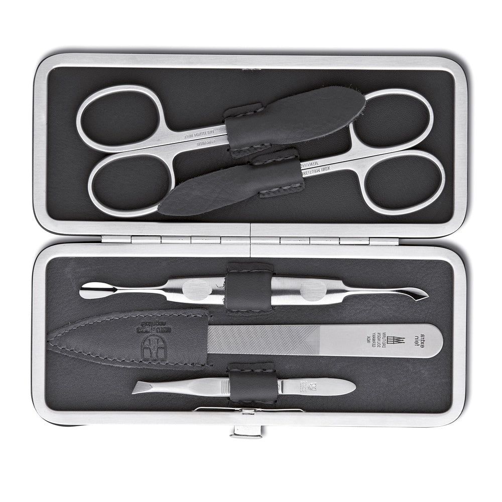 Maniküre-Etui mit Schere, Nagelfeile, Hautschieber und Pinzette. Schwarzes Leder, silberfarbene Werkzeuge. Geöffnet.