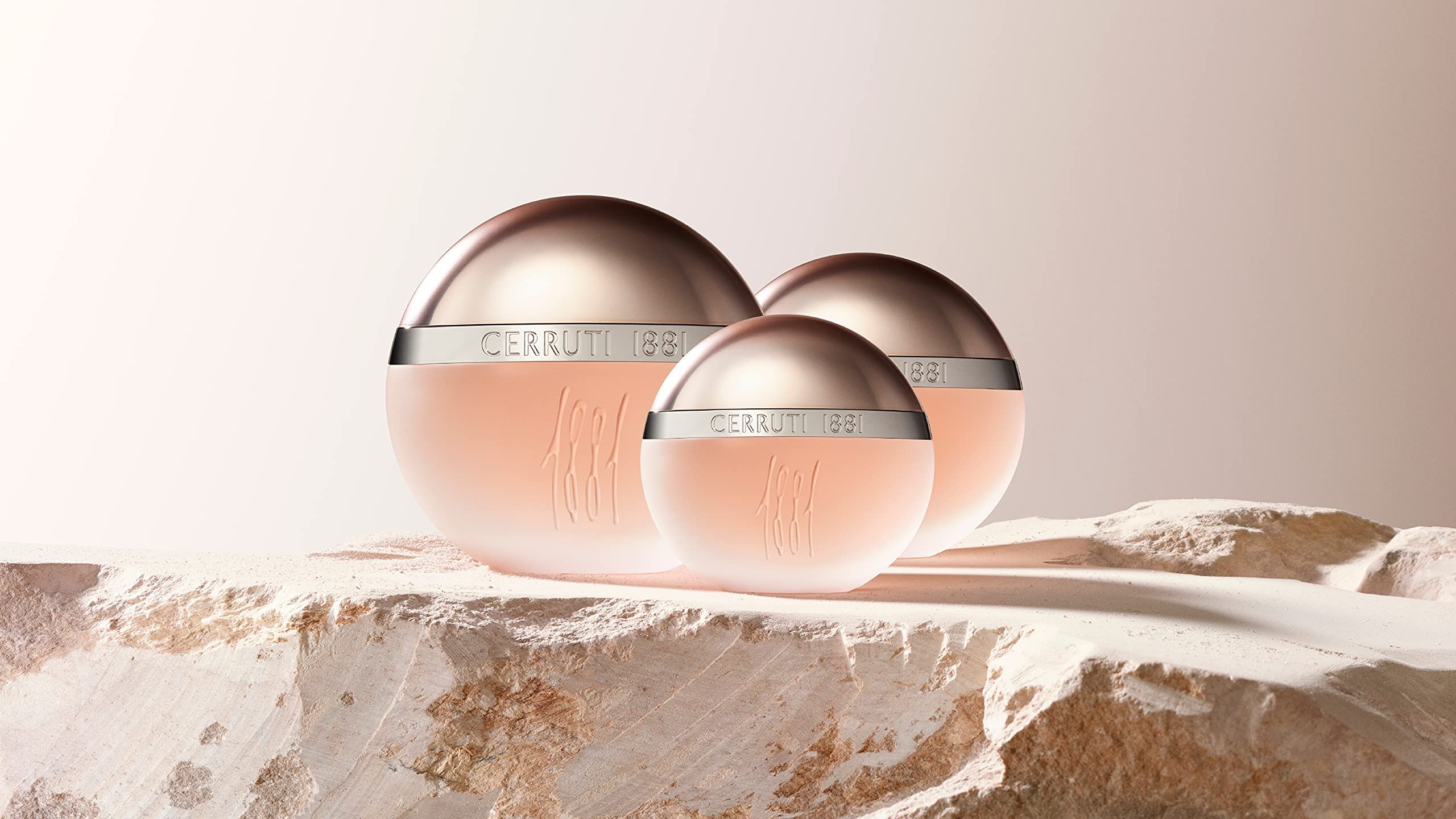 Drei Flakons auf einer Oberfläche. Flakons mit silbernen Deckeln und Schriftzug Cerruti 1881. Rosa Flüssigkeit.