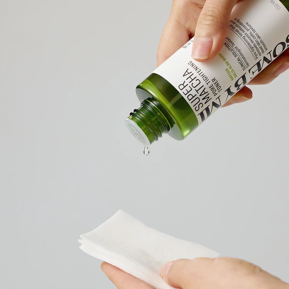 Grüner Toner wird auf ein Wattepad getropft. Das Produkt hat einen weißen Aufkleber mit schwarzer Schrift.