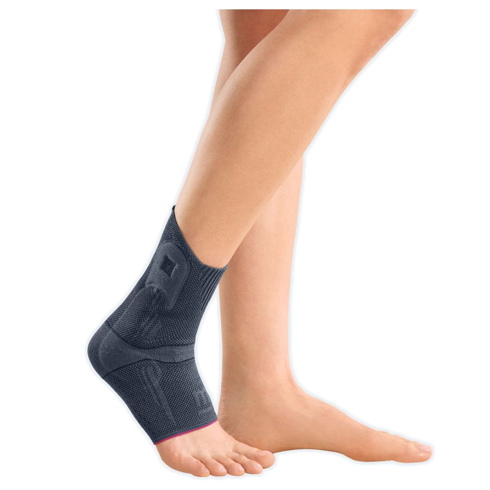Graue Sprunggelenkbandage am Bein. Roter Akzent am Saum. Zeigt das Produkt am Fuß. Ohne Kreuzgurte.