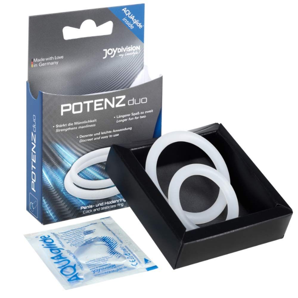 Zwei weiße Penisringe in einem schwarzen Präsentationskästchen, daneben eine kleine Packung Gleitmittel.