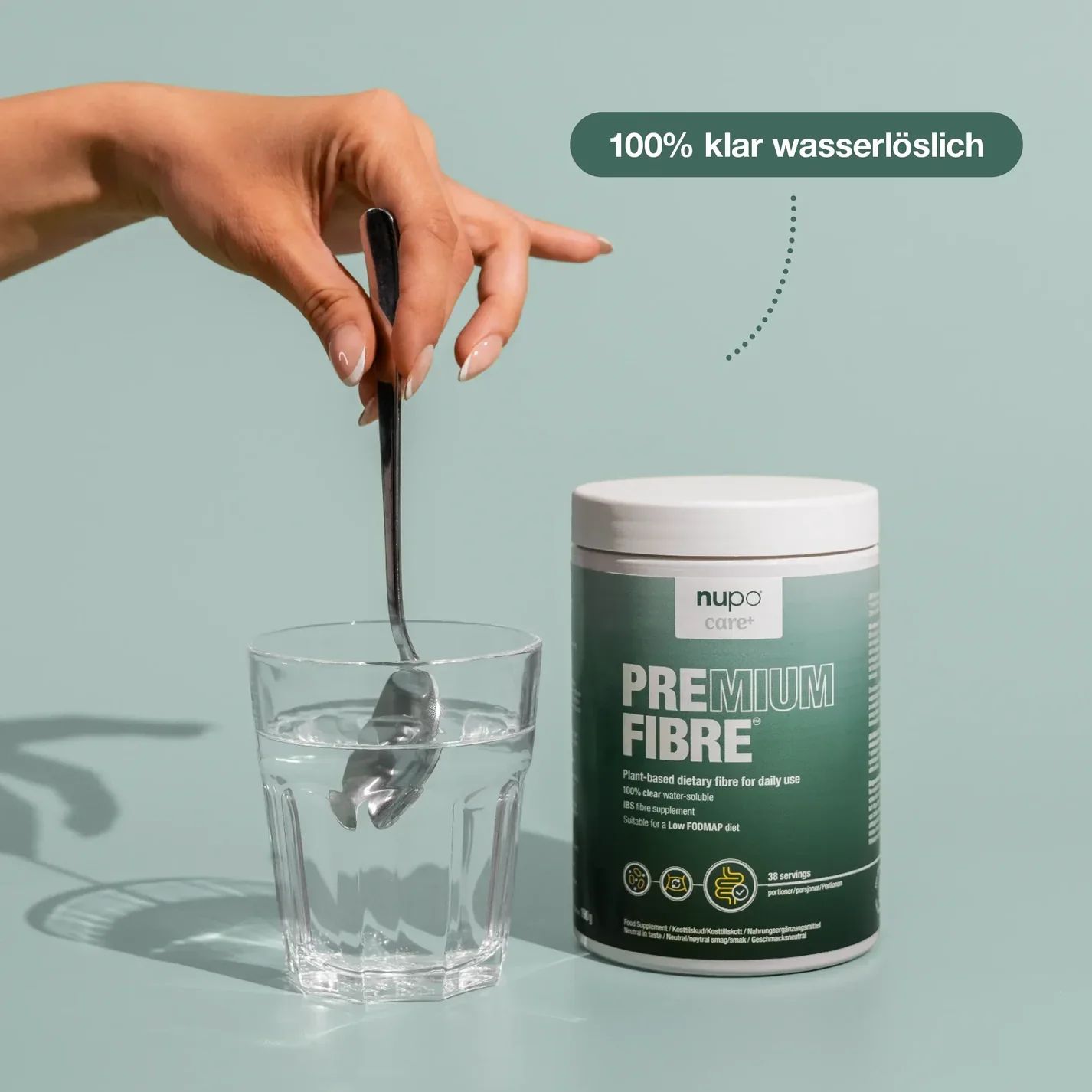 Hand mit Löffel über Glas Wasser. Dose mit grünem Etikett. Aufschrift: PREMIUM FIBRE. Marke: nupo care. Text: 100% klar wasserlöslich, 30 Portionen.