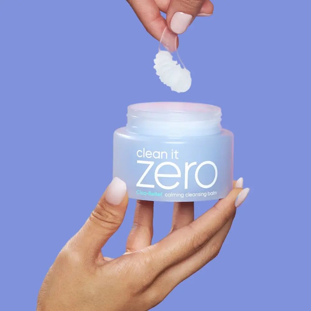 Hände halten einen Tiegel und einen Spatel mit Produkt. Produkt: clean it zero, blauer Tiegel mit weißem Deckel.