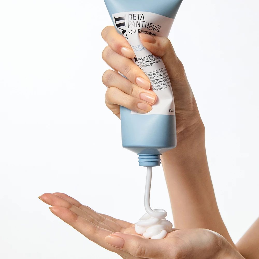 Creme wird aus einer blauen Tube in die Hand gedrückt. Produktname und Text sind sichtbar.