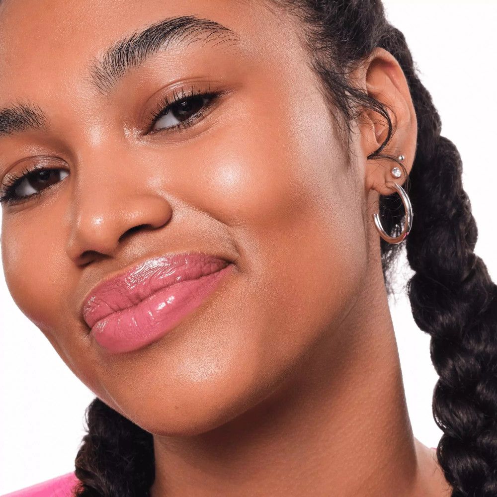 Porträt einer Frau mit rosa Lipgloss. Dunkle Haut, geflochtene Haare. Nahaufnahme.