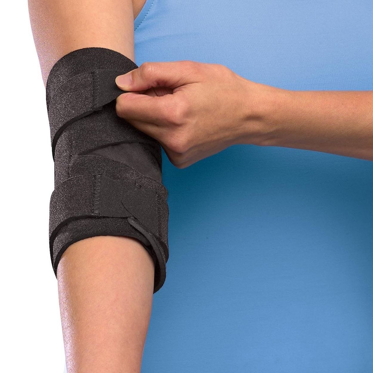 Personne portant une attelle de coude noire. Fermeture velcro en cours.