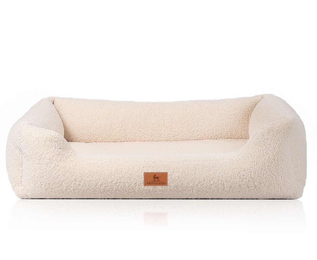 Beige orthopädisches Hundebett mit erhöhten Seiten und einem rechteckigen Markenetikett.