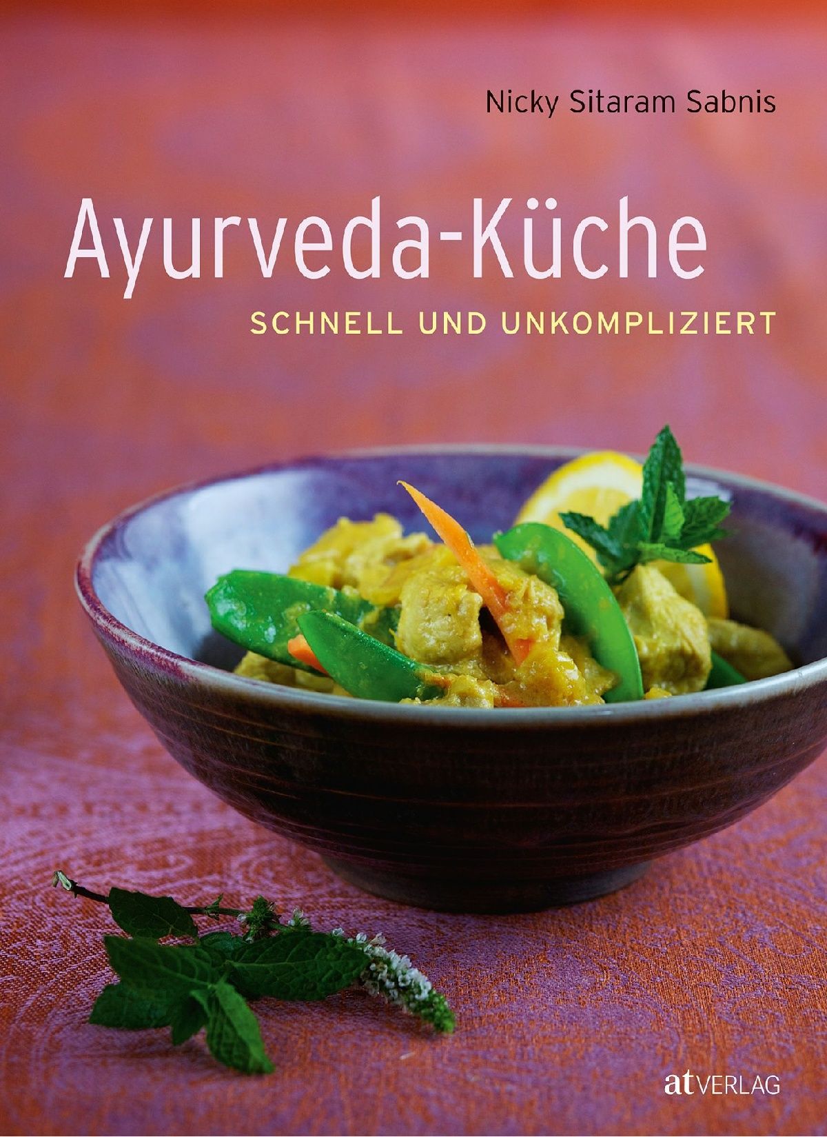Buchcover: "Ayurveda-Küche" von Nicky Sitaram Sabnis. Gericht in Schüssel, mit Gemüse und Zitrone. Auf rotem Stoff.