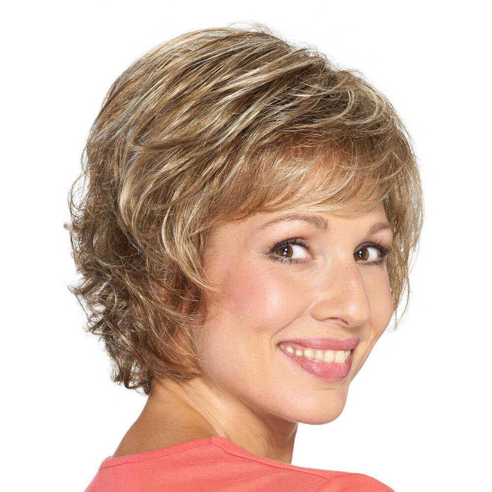 Kurzhaarperücke mit gewelltem, blond-braunem Haar. Die Frau lächelt und blickt über die Schulter. Rosa Oberteil.