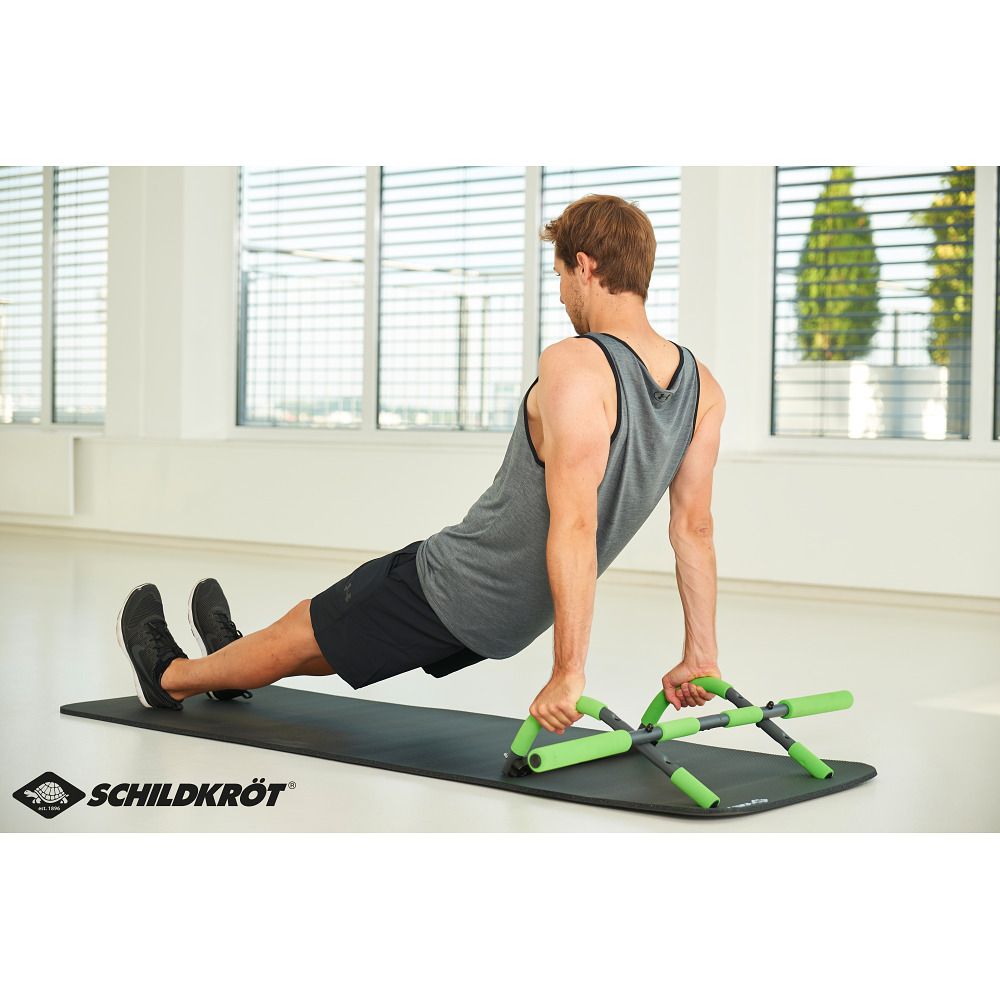 Mann trainiert mit dem Schildkröt Türreck Multifunktional 4 in 1. Das Gerät liegt auf einer Matte. Griffe grün.