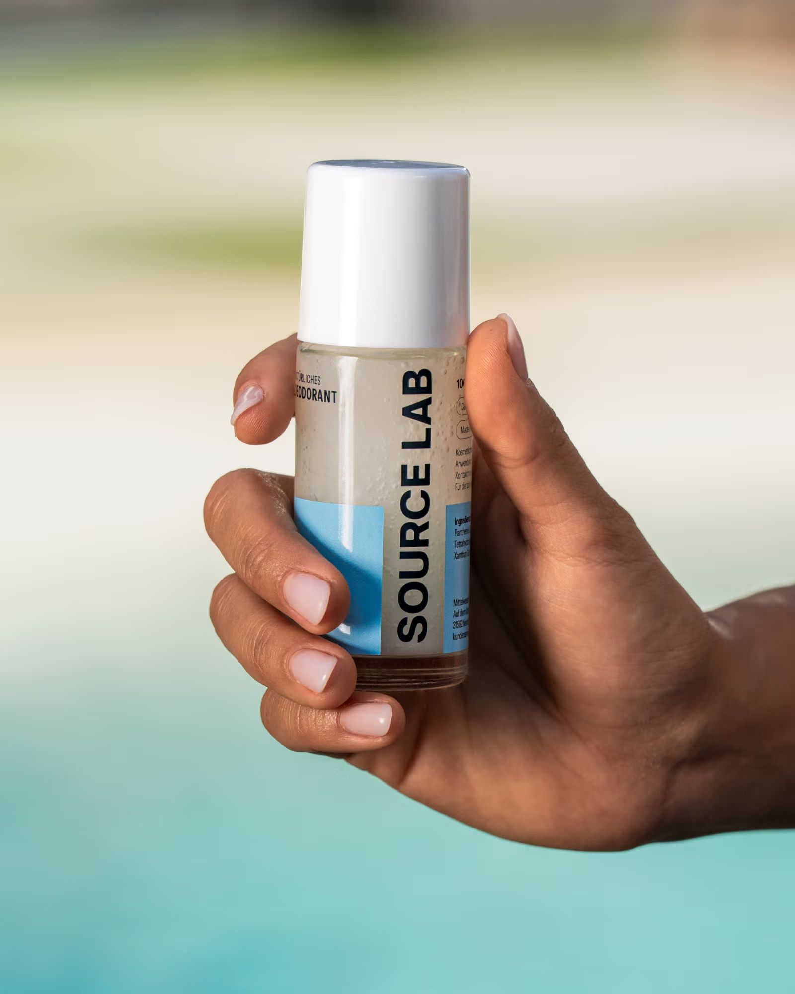 Hand hält SOURCE LAB Natürliches Deodorant Roll-on Sensitiv.
