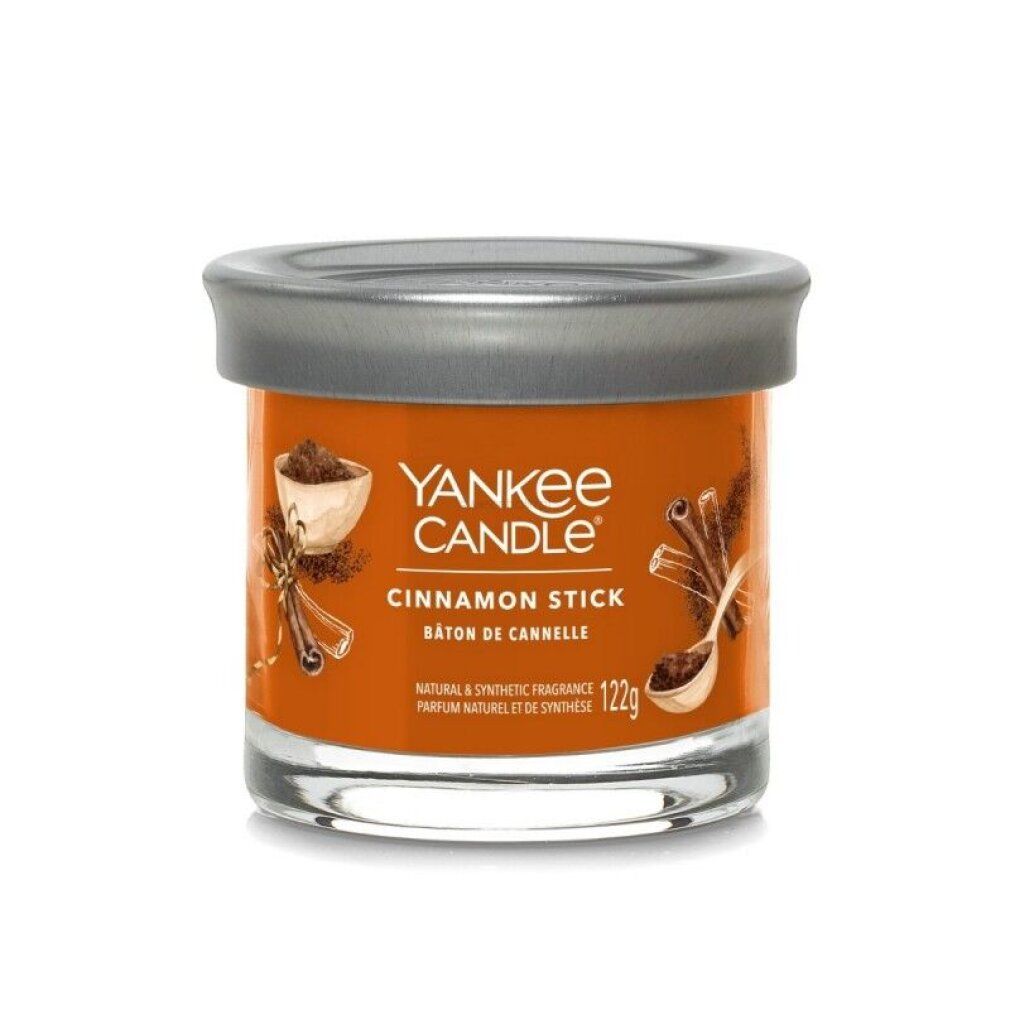 Zylinderförmige Kerze mit Deckel. Aufschrift: Yankee Candle, Cinnamon Stick. Orangefarbenes Wachs in einem Glasbehälter.