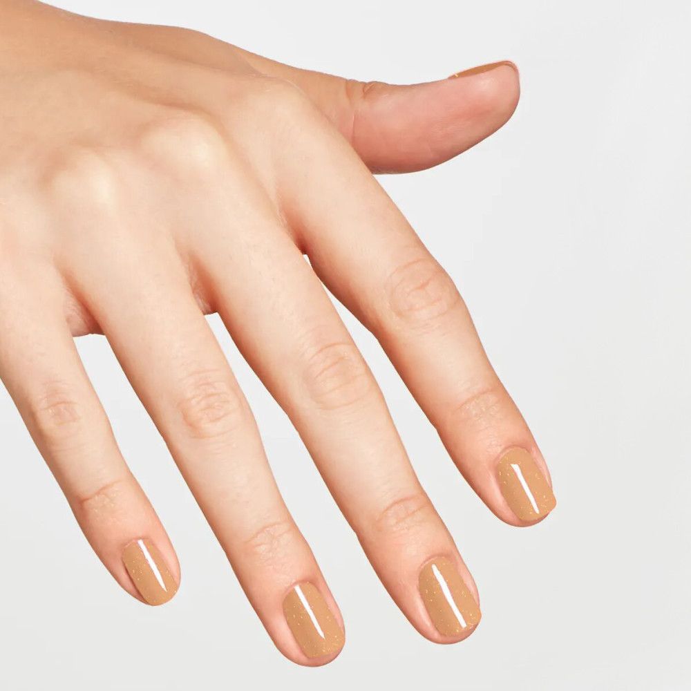 Hand mit lackierten Nägeln. Beige Nagellack.