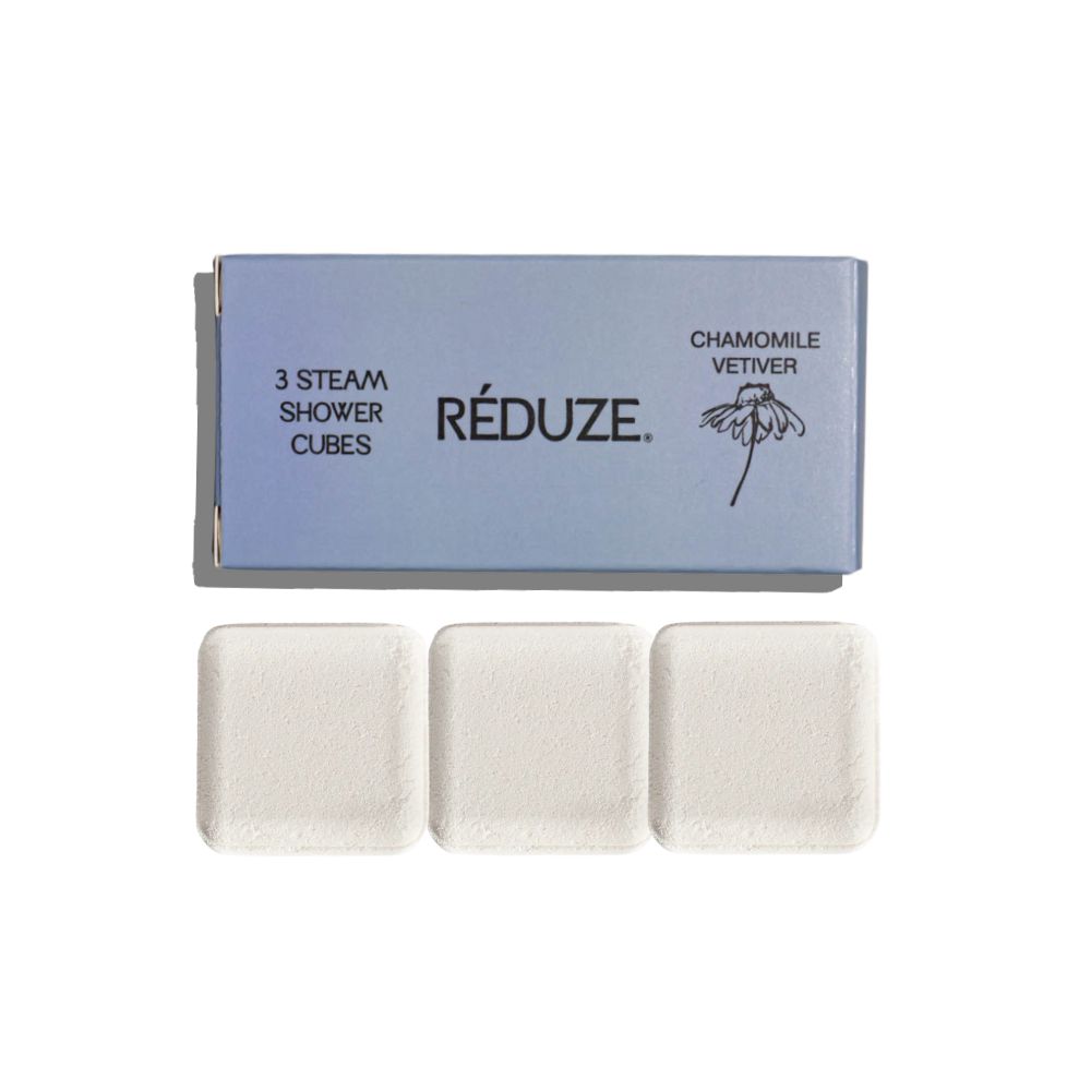 Drei quadratische Duschwürfel und eine Schachtel. Auf der Schachtel steht RÉDUZE und Kamille & Vetiver.