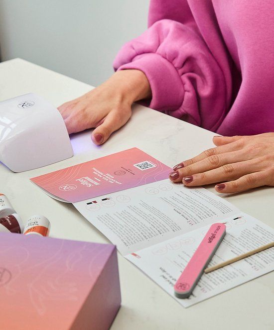 Person mit Maniküre. UV-Lampe, Broschüre und Feile. Aufschrift: selfgel manual. PN-Logo.