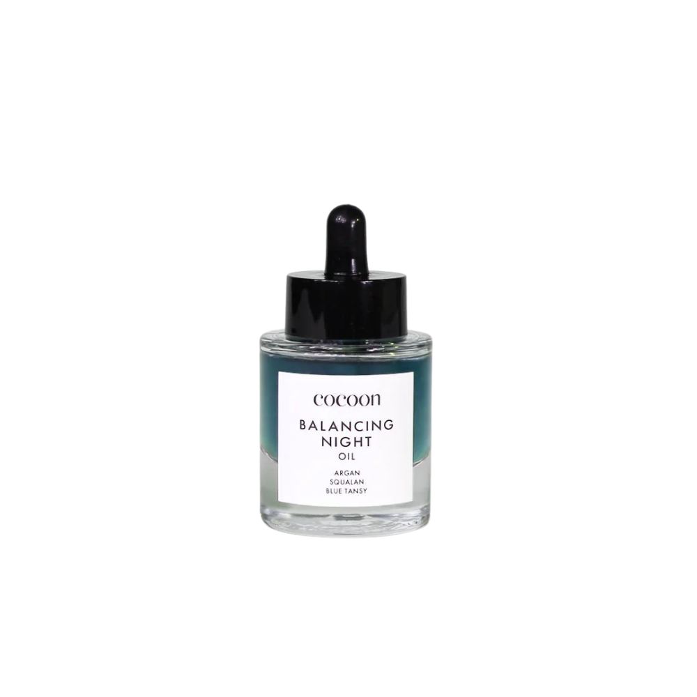 Glasflasche mit schwarzem Tropfer. Aufschrift: Cocoon Balancing Night Oil. Enthält Argan, Squalan, Blue Tansy.