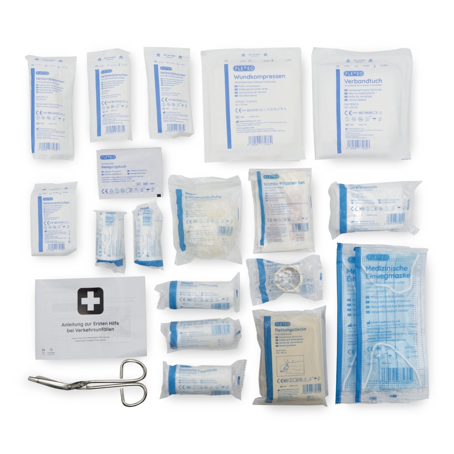 Inhalt einer KFZ-Verbandtasche. Verschiedene Verbandsmaterialien, Kompressen, Pflaster, Schere. Einzeln verpackt in weiß-blauen Folien. Anleitung zur Ersten Hilfe.
