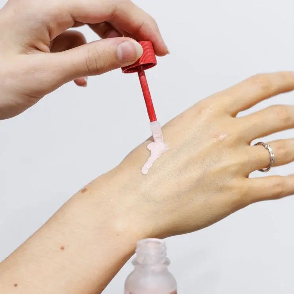Applikator mit rosa Pulver auf einer Hand aufgetragen.