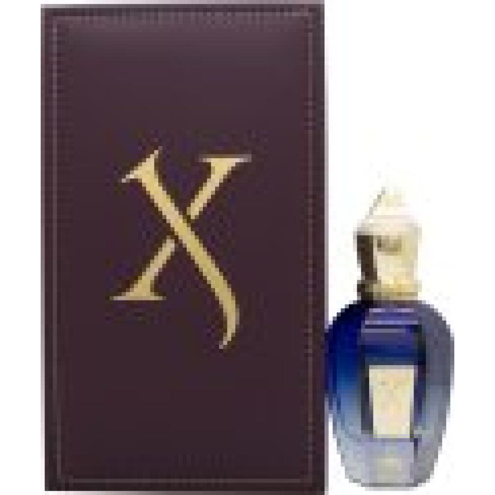 Parfümflakon neben einer braunen Schachtel. Auf der Schachtel ein goldenes "X".