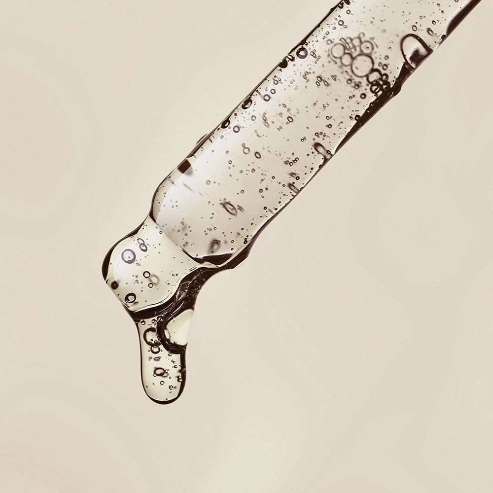 Nahaufnahme einer Pipette mit Serum. Klare Flüssigkeit mit Blasen. Tropfenbildung.