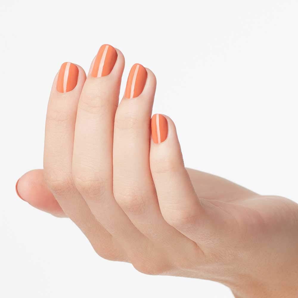 Hand mit lackierten Nägeln. Die Nägel sind mit orangefarbenem Nagellack lackiert.