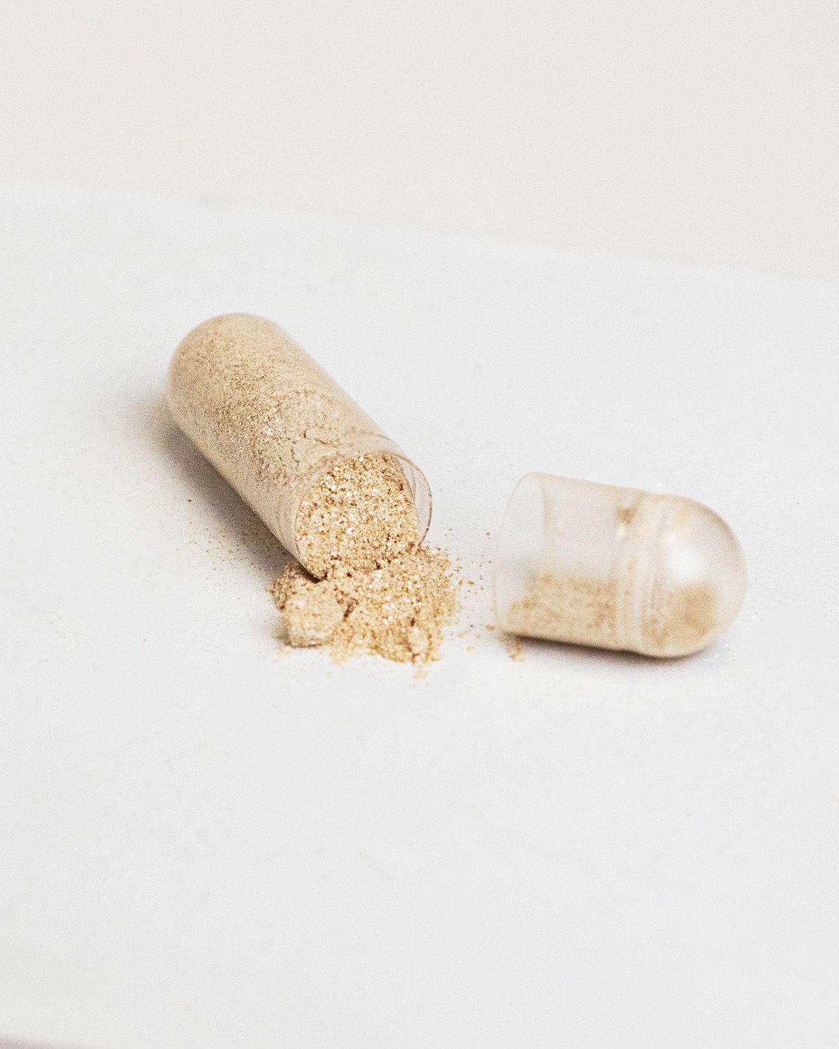 Geöffnete Kapsel mit hellbraunem Pulver. Kapsel ist transparent.