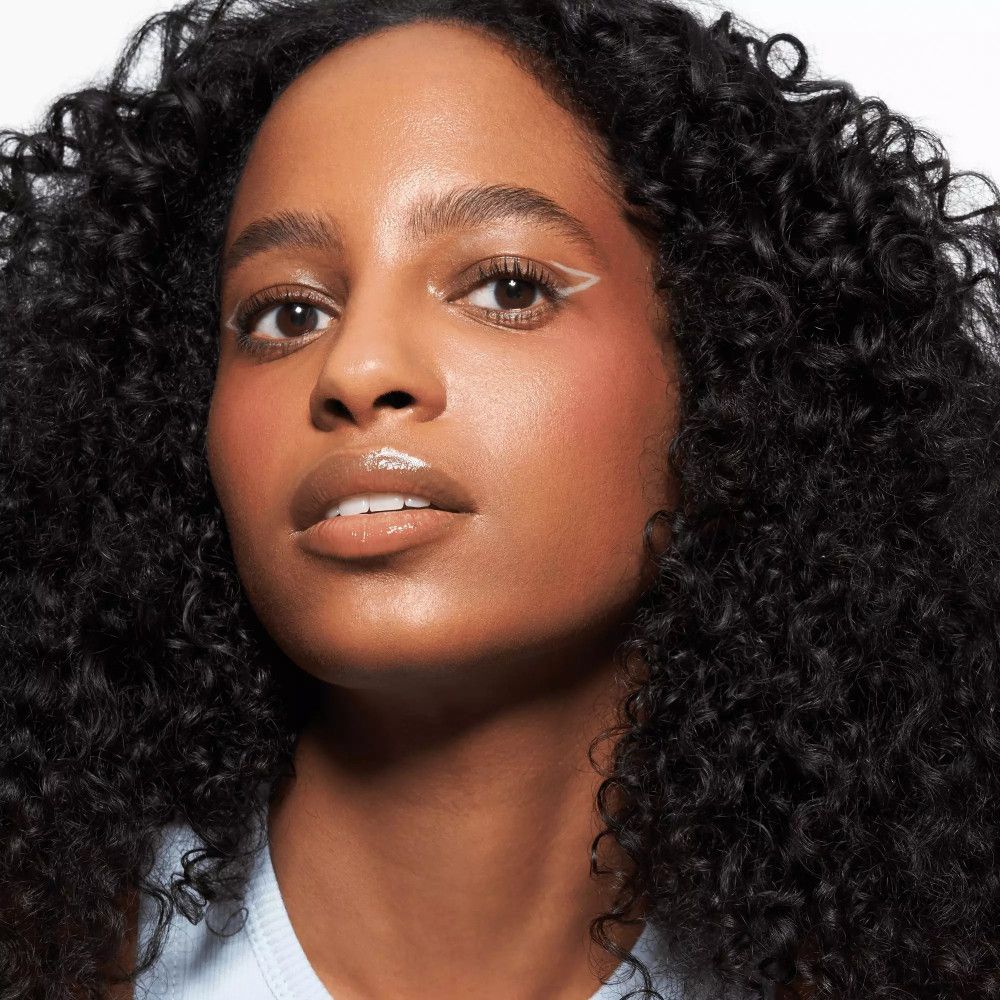 Porträt einer Frau mit hellem Kajalstrich am Auge. Lippen und Wangen geschminkt.