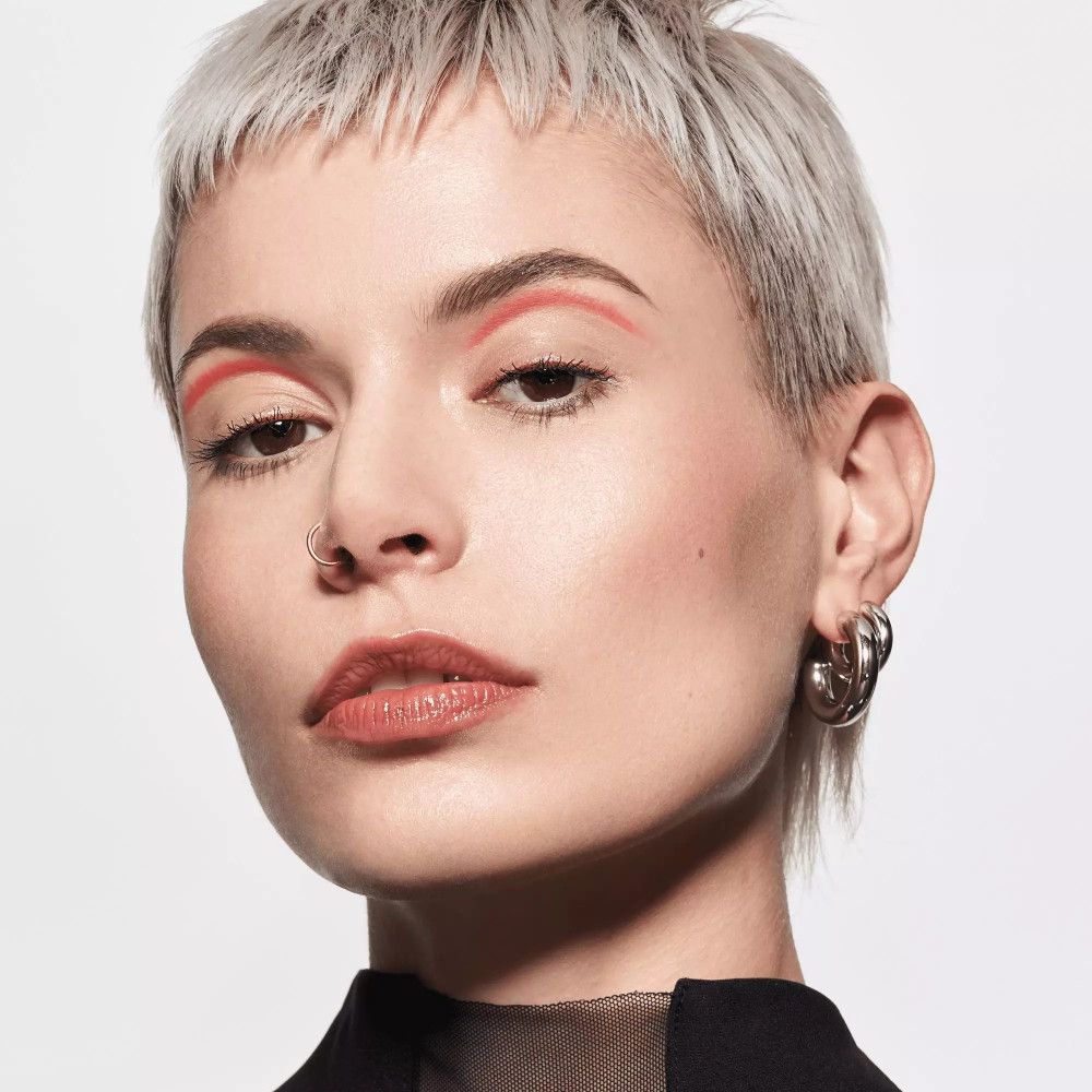 Frau mit kurzen Haaren und Lippenstift. Sie lächelt. Lippen glänzend.