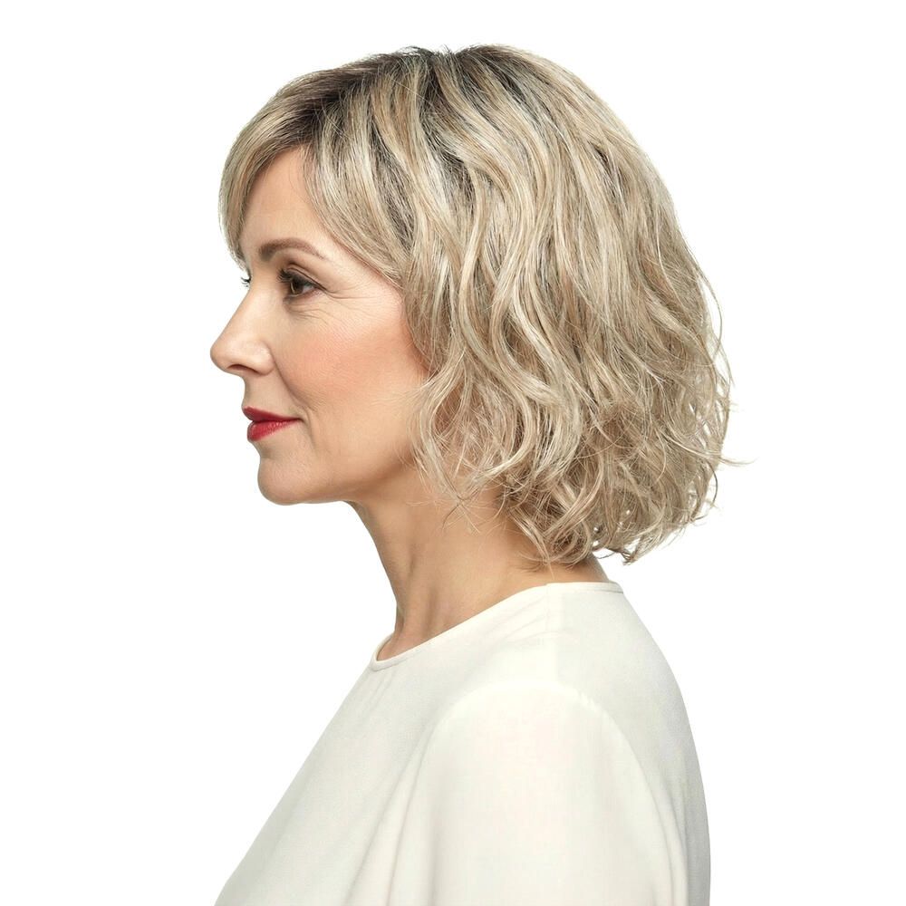 Perücke Capri von DELUXE. Blond gewellt, mit Pony. Frau mit Perücke, Seitenansicht.