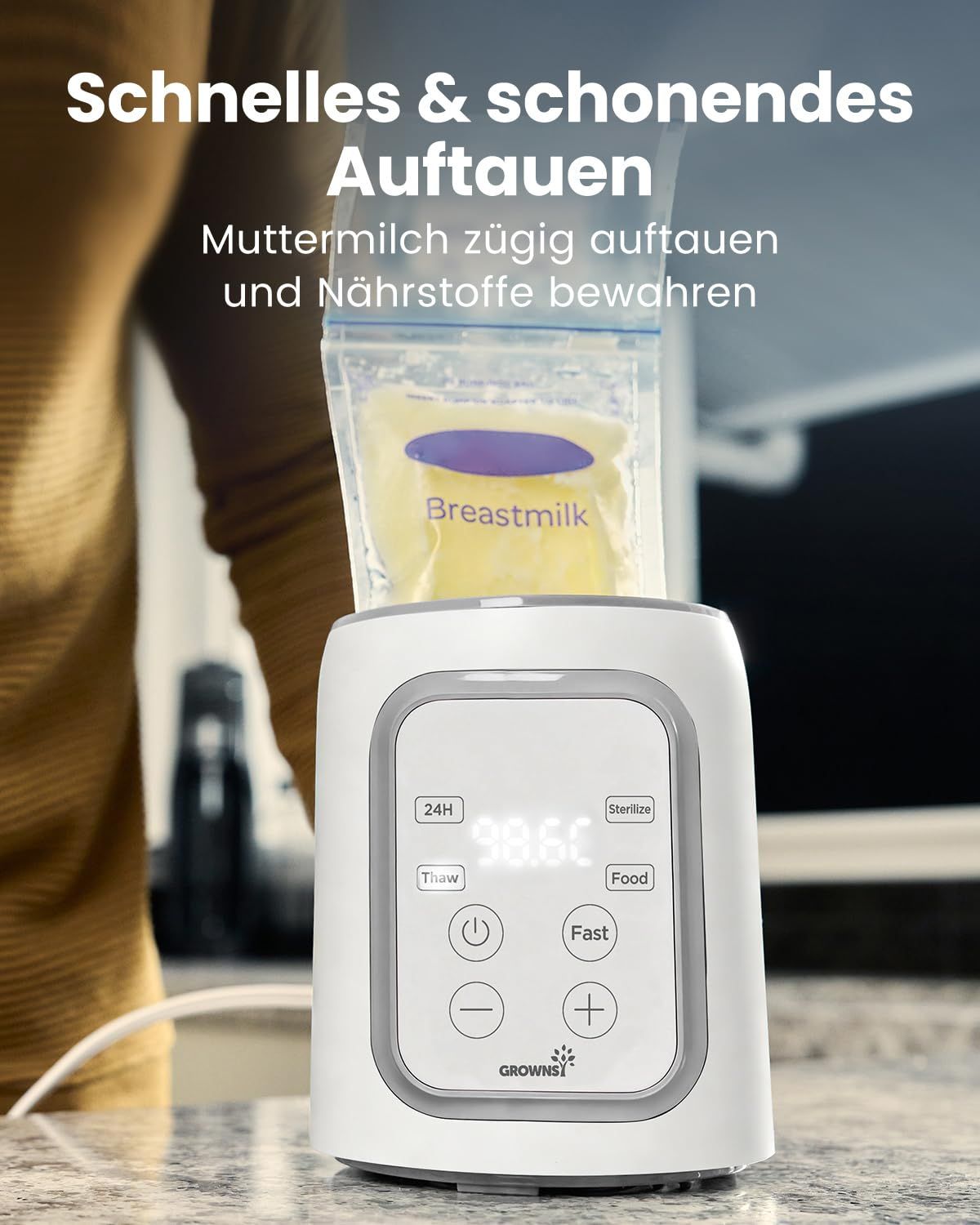 Ein weißer Flaschenwärmer mit digitaler Anzeige (98.6°C) und Bedienelementen. Eine "Breastmilk"-Tüte ist oben platziert.