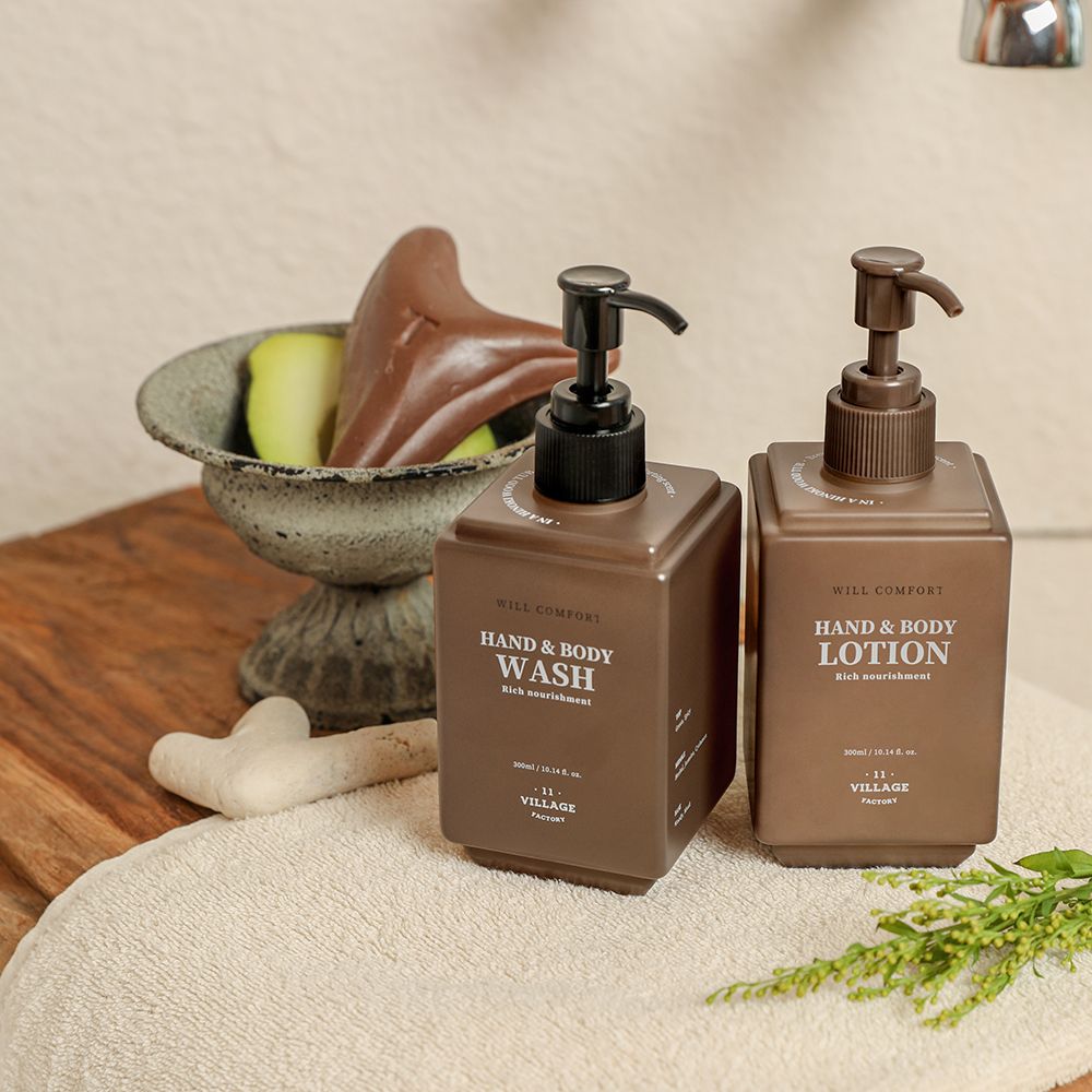 Zwei braune Lotion-Flaschen mit Pumpen. Aufschrift: Hand & Body Wash und Hand & Body Lotion. Marke: VILLAGE 11 FACTORY.