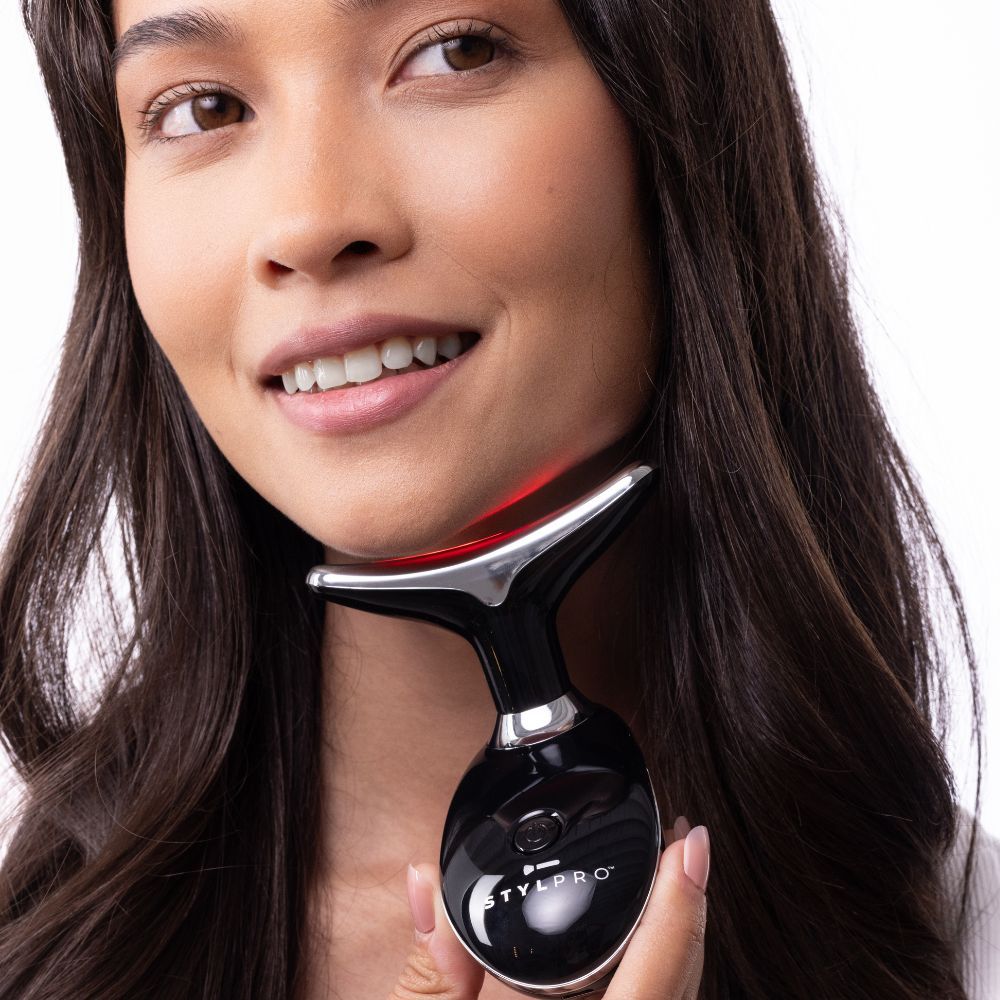 Frau hält STYLPRO-Gerät am Hals. Schwarzes Gerät mit silberfarbenem Kopf. Rotes Licht leuchtet am Kopf.
