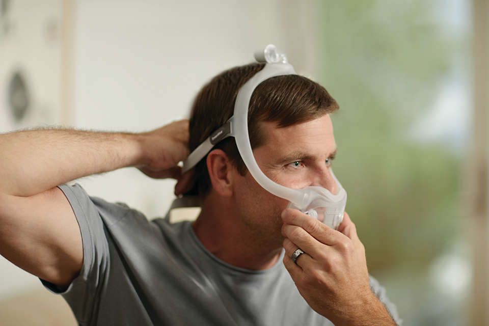 Mann passt Philips CPAP DreamWear Vollgesichtsmaske an.