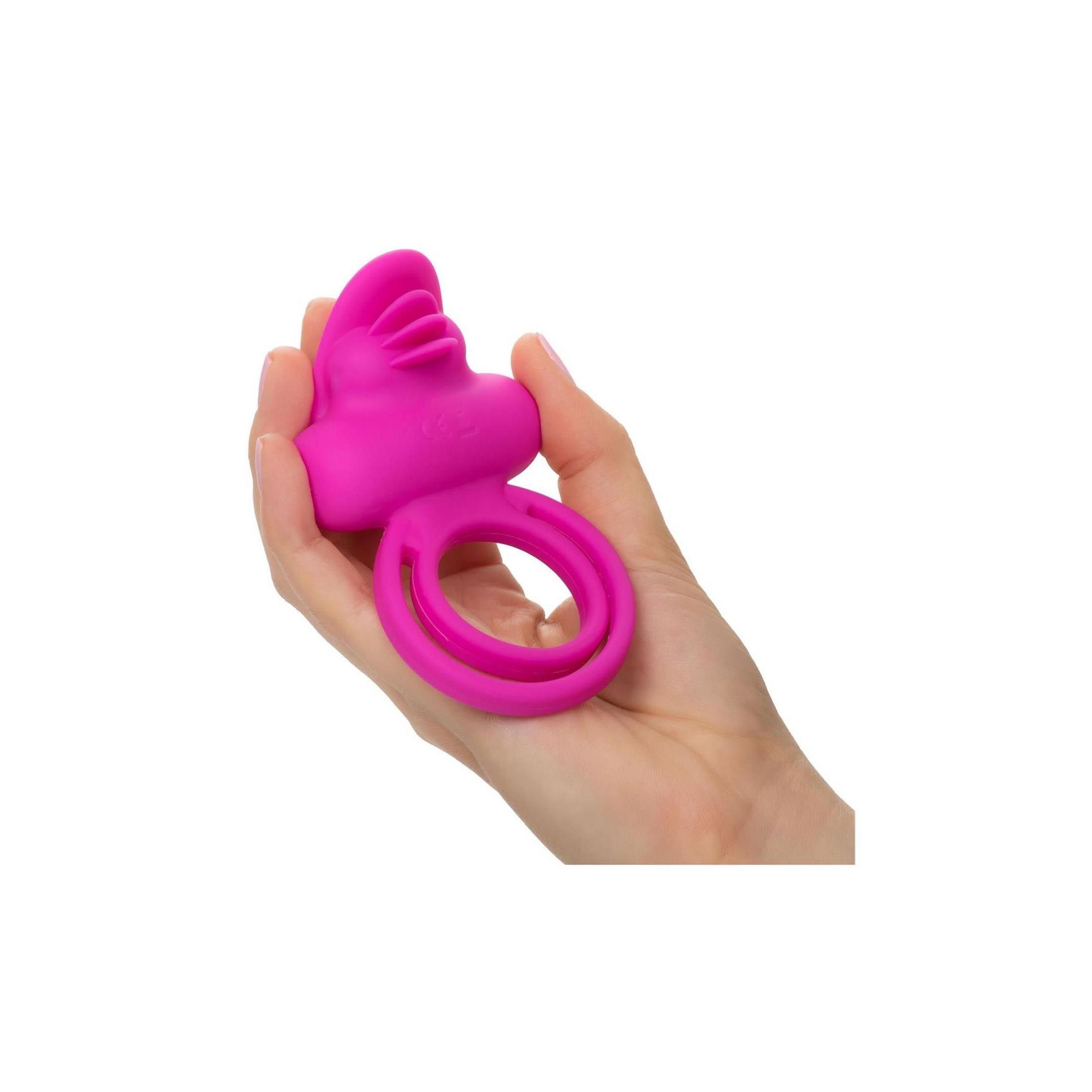 Rosa Clit Flicker Enhancer. In Hand gehalten. Ringförmig mit zwei Öffnungen. Oberteil mit geriffelter Oberfläche.