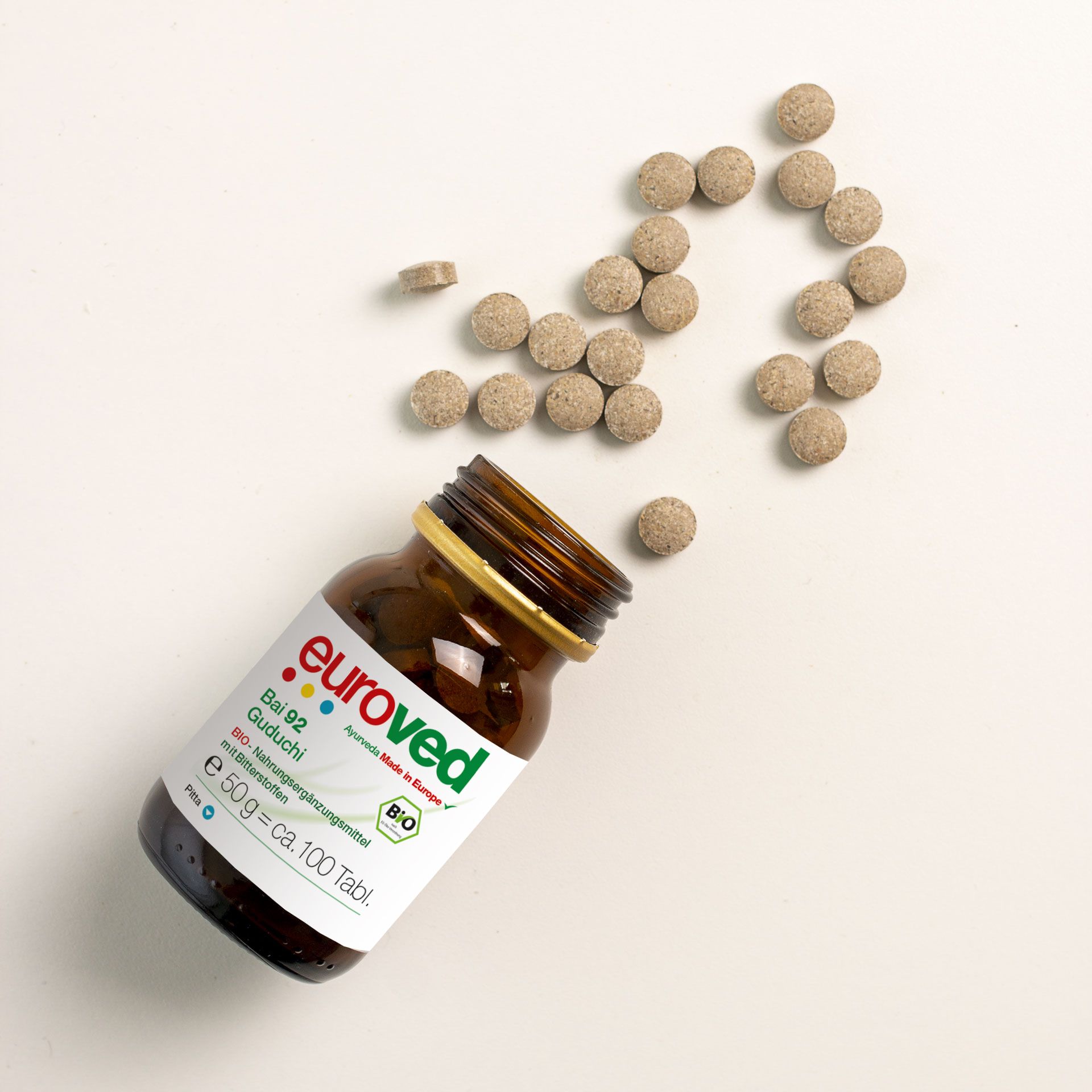 Braune Glasflasche mit goldfarbenem Deckel und Etikett "euroved". Daneben Tabletten verstreut. Bio-Siegel sichtbar.