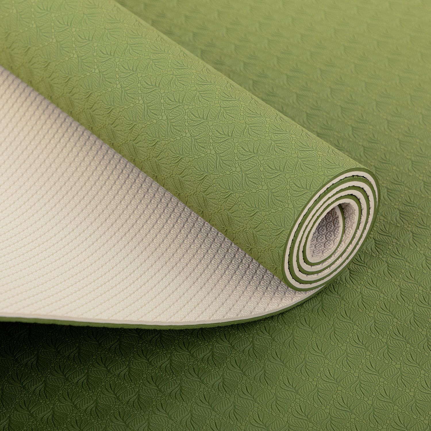 Gerollte Yogamatte, grün. Oberseite mit Muster, Unterseite hell. Detailansicht der gerollten Kante.