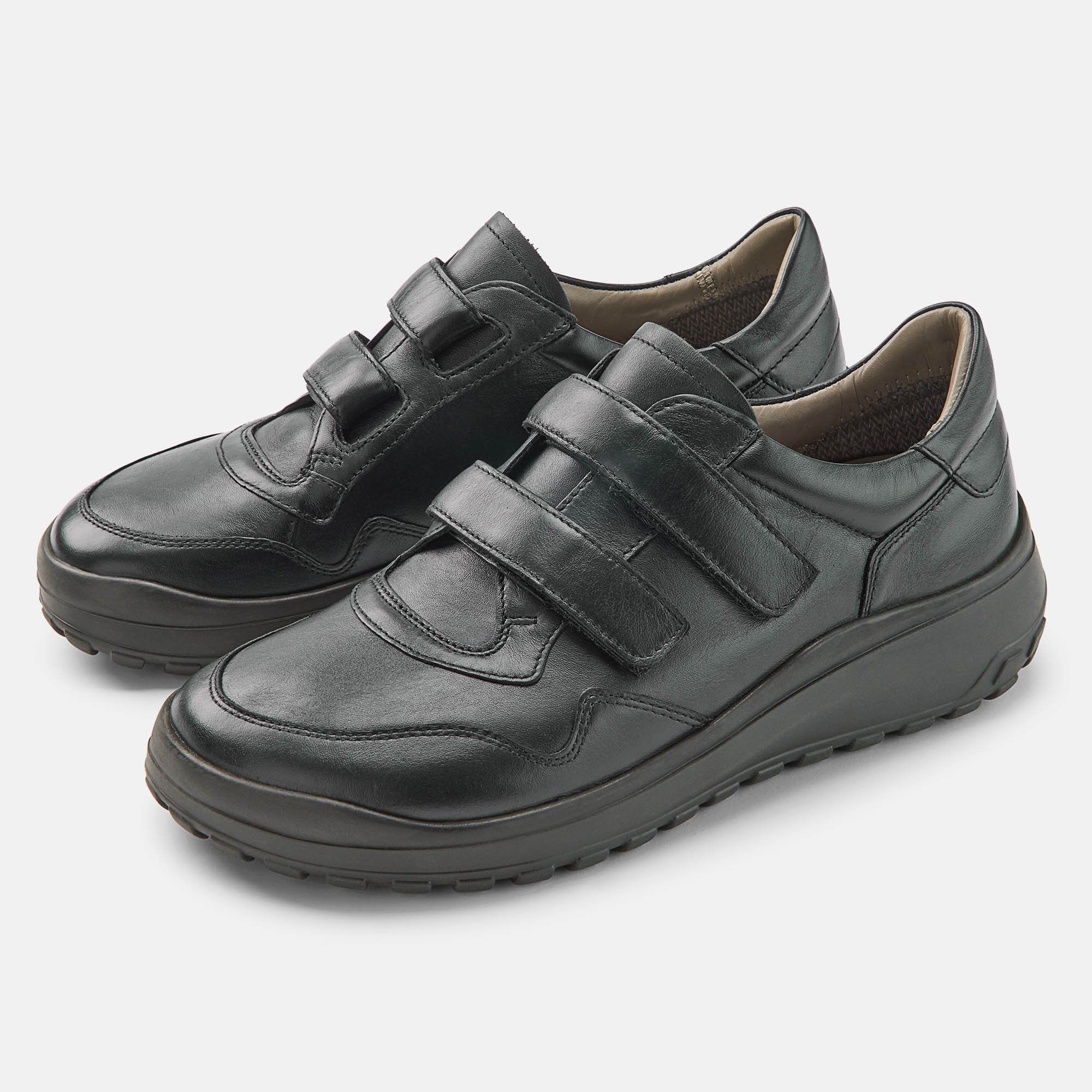 Schwarze Herren-Slipper mit Klettverschluss. Breite Passform. Zwei Schuhe nebeneinander, leicht schräg gestellt.