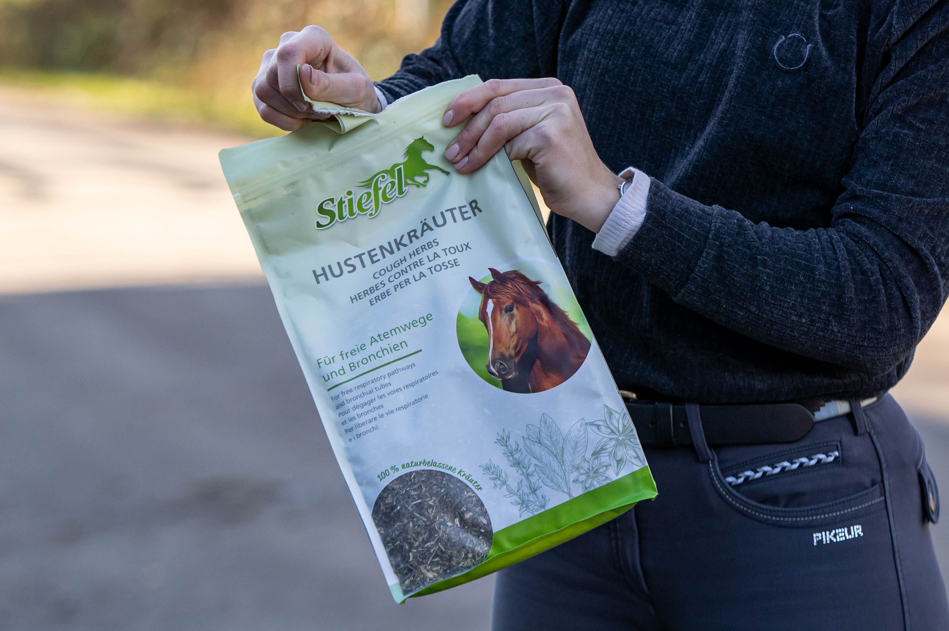 Person hält einen Beutel Stiefel Hustenkräuter. Aufschrift: Für freie Atemwege und Bronchien. Produktbeutel wird geöffnet.