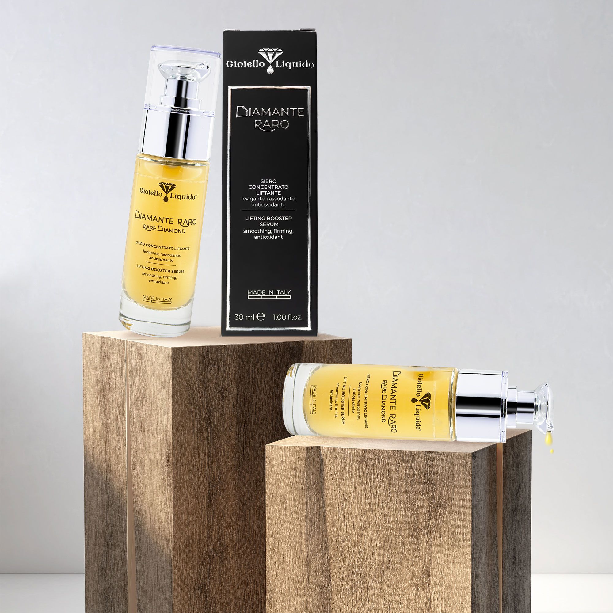 Flaconi di siero e confezione su blocchi di legno. Scritta: Gioiello Liquido, Diamante Raro, Lifting Booster Serum. 30 ml.