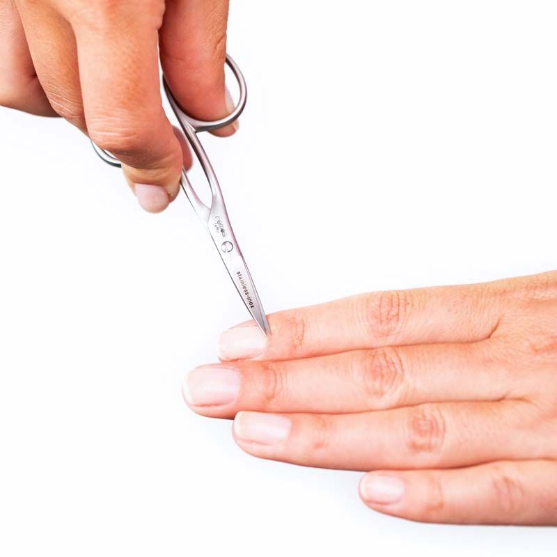 Nagelschere für Linkshänder schneidet einen Fingernagel. Die Schere ist aus Metall und wird von einer Hand gehalten.