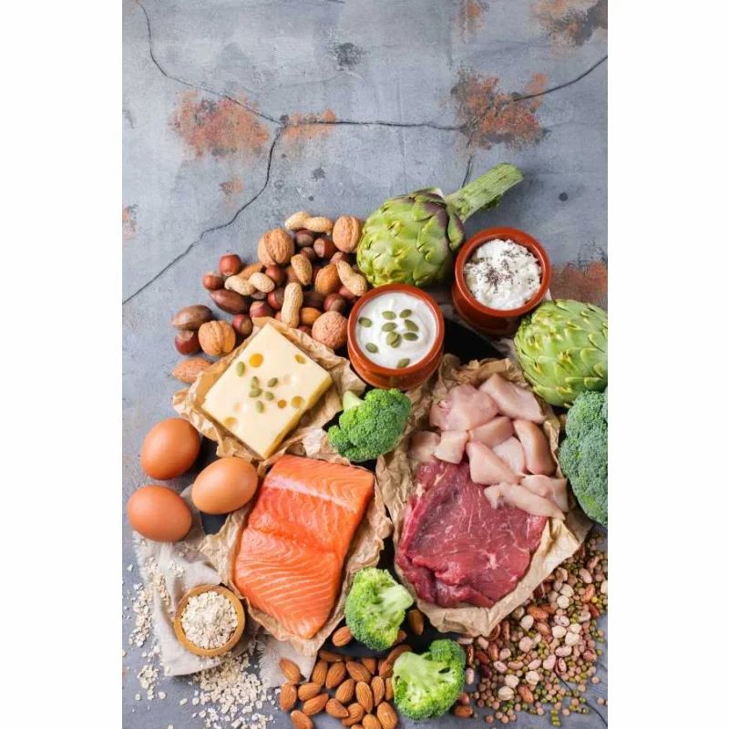 Draufsicht auf eine Auswahl an Lebensmitteln: Fisch, Fleisch, Eier, Nüsse, Gemüse und Hülsenfrüchte.